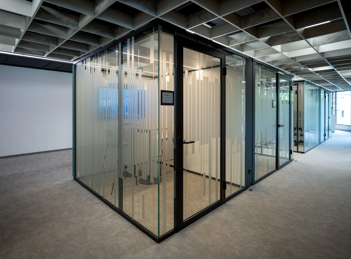 Raum-in-Raum-Systeme im Open Office mit bedruckten Glas und Stoffbespannung petrolfarbend außen. 
