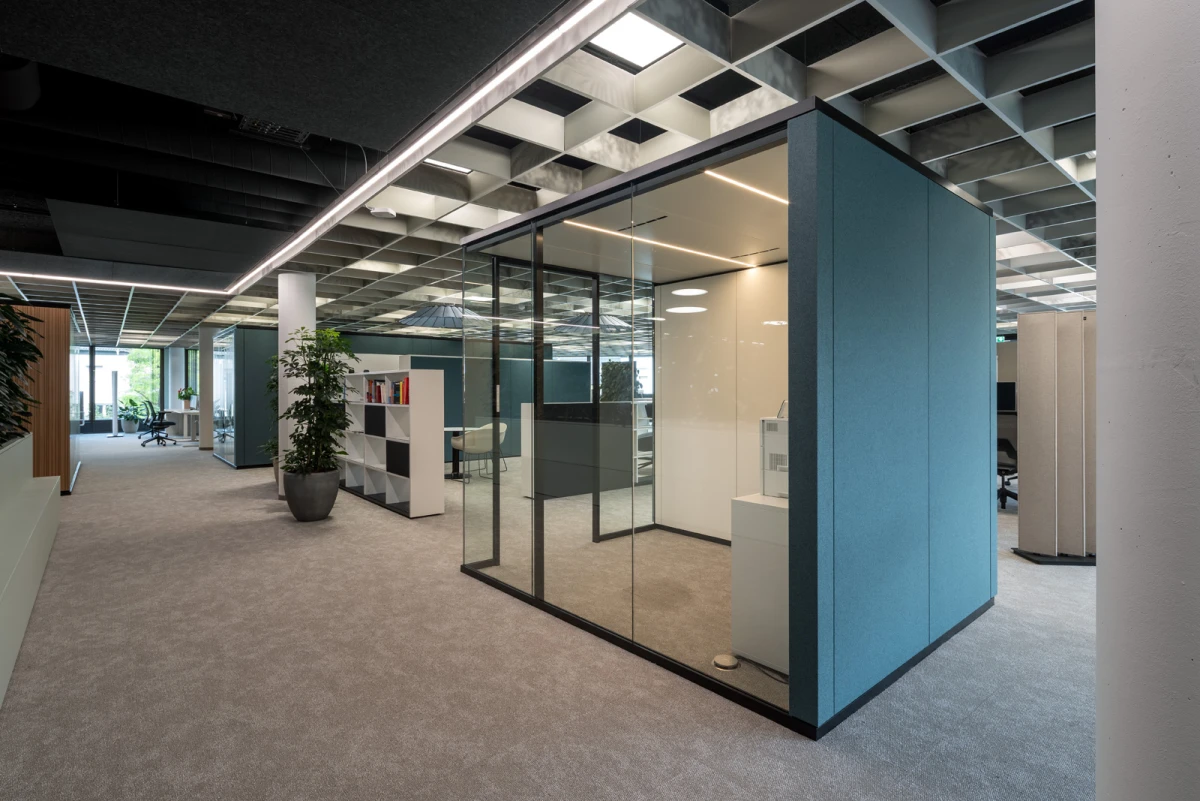 Raum-in-Raum-Systeme im Open Office mit bedruckten Glas und Stoffbespannung petrolfarbend außen. 