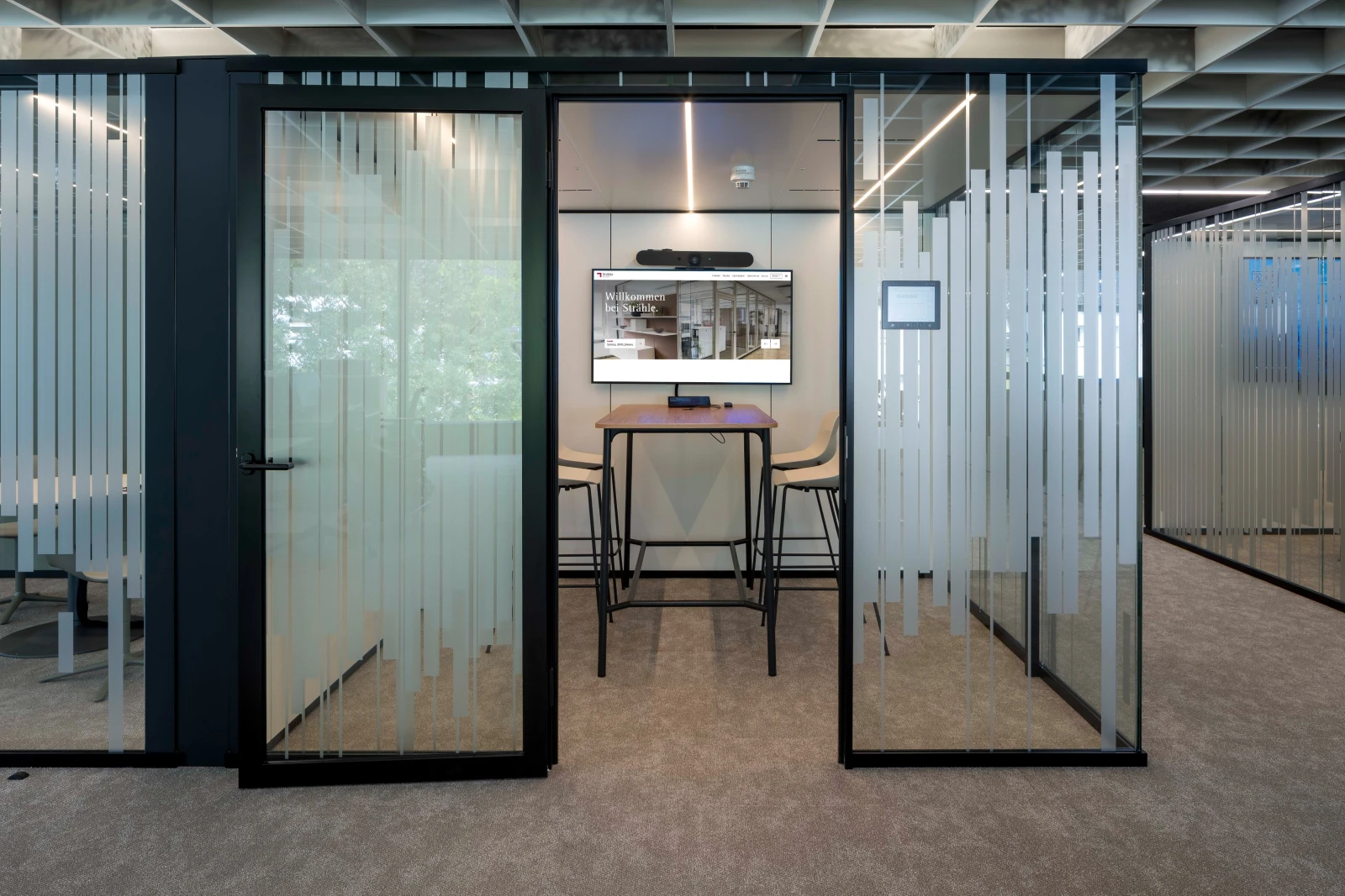 Raum-in-Raum-Systeme im Open Office mit bedruckten Glas und Stoffbespannung petrolfarbend außen. 