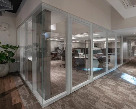 Elegante Glasarchitektur teilt einen modernen Showroom in verschiedene Arbeitsbereiche.