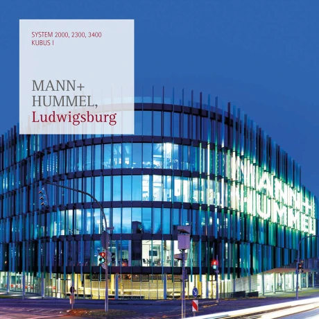 Modernes, geschwungenes Glasgebäude von Mann+Hummel in Ludwigsburg. Die Fassade ist durch reflektierende Glasflächen gekennzeichnet.